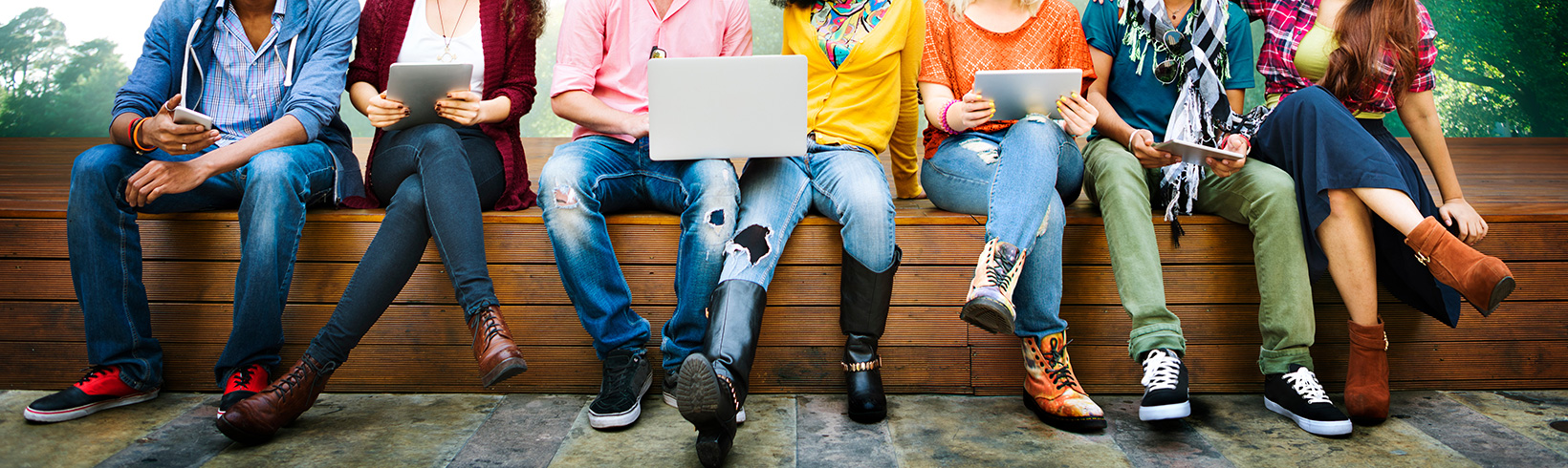 Students on a bench with tech